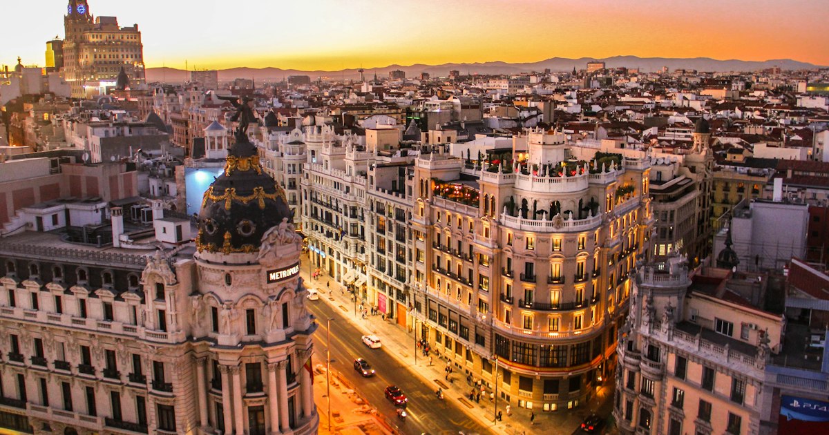 Vista panorámica de la Gran Vía de Madrid al atardecer con edificios históricos iluminados